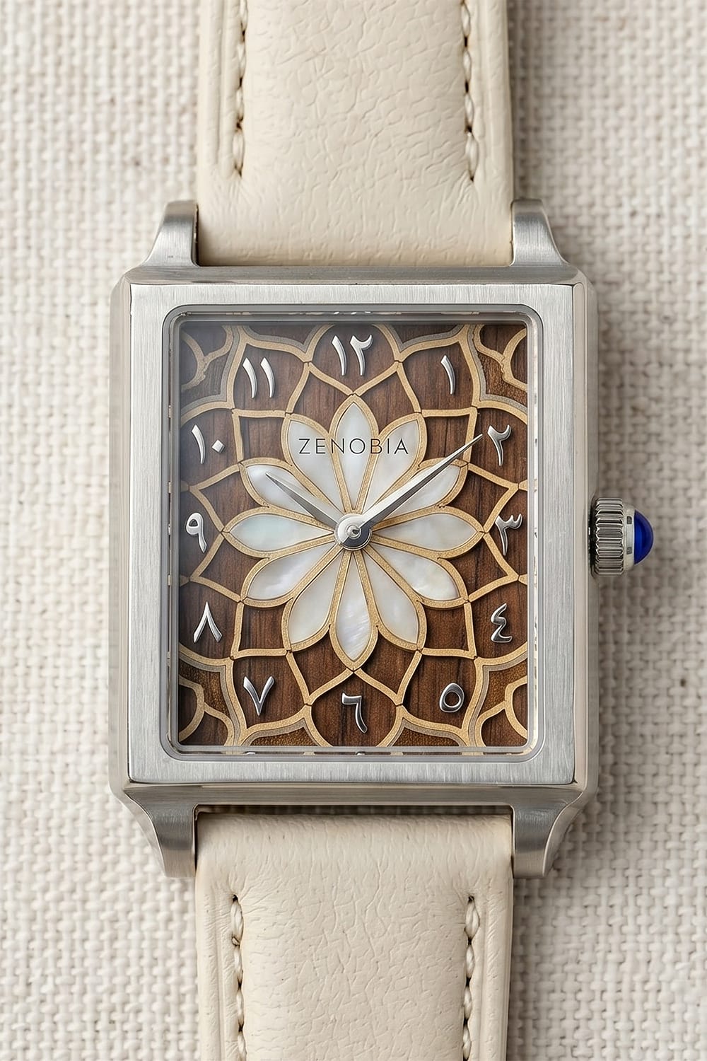 Close view of a Zenobia dial with a pearl flower and fine gold-coloured geometry over a wood-toned ground